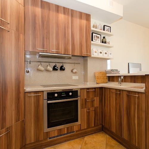 A contemporary kitchen design showcasing wooden cabinets, open shelves, and stainless steel appliances.