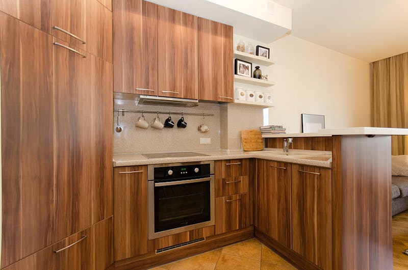 A contemporary kitchen design showcasing wooden cabinets, open shelves, and stainless steel appliances.